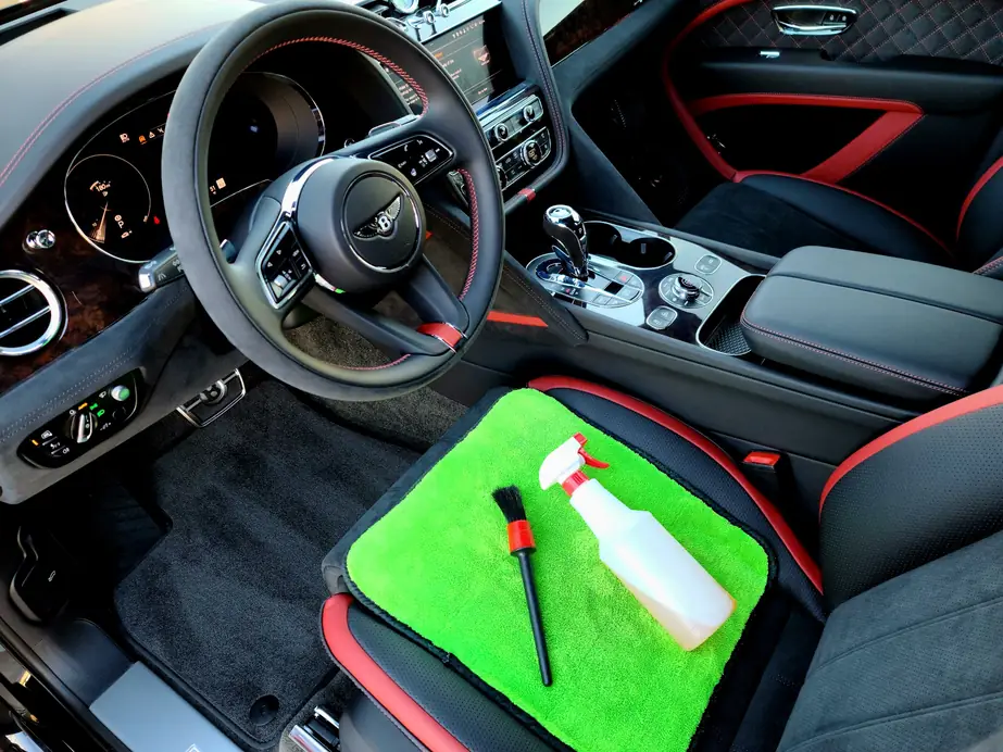 Black and red Bentley interior with a detailing brush and spray bottle on the console