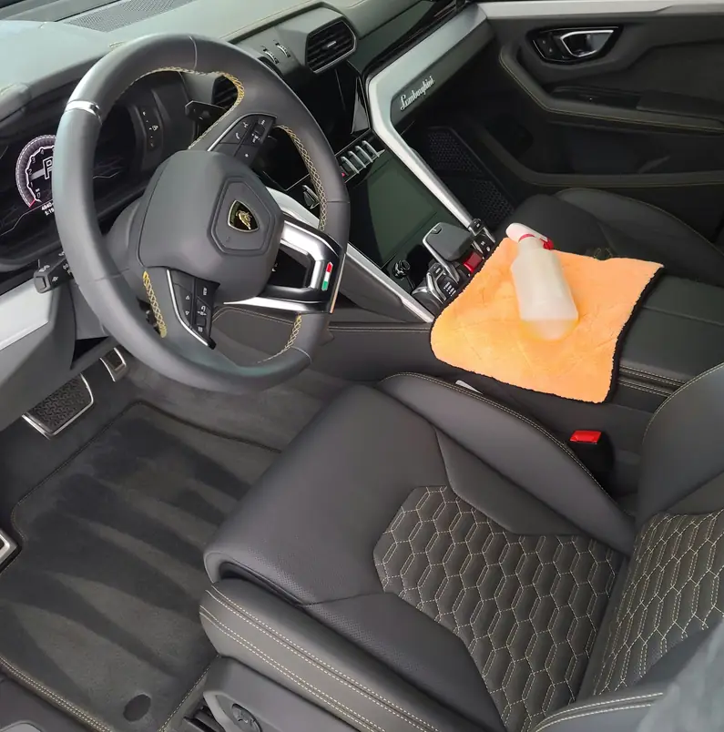 Lamborghini Urus interior with an orange microfibre towel and spray bottle on the console