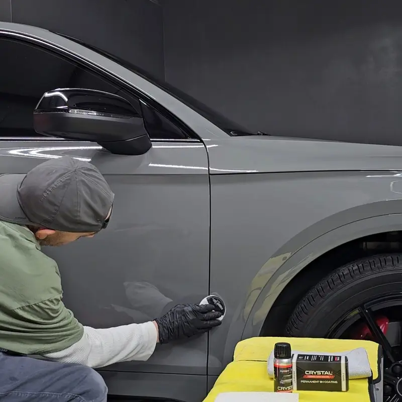 Technician applying System X Crystal coating to the door of a grey Audi in the studio